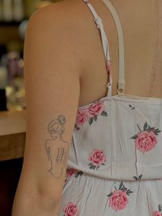 the back of a woman's dress with pink flowers on it and a tattoo