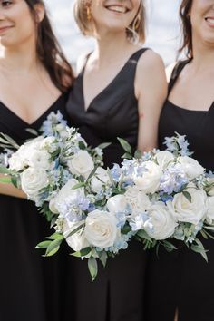 three bridesmaids in black dresses holding bouquets with white and blue flowers on them