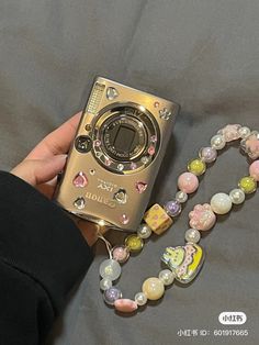 a person holding a camera next to a beaded necklace