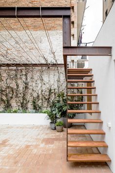 a wooden staircase next to a brick wall and potted plants on the side walk