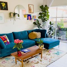 a living room with blue couches and potted plants on the table in front of a large window