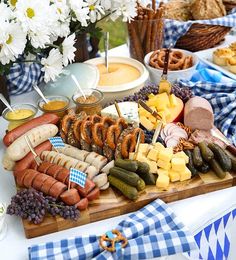 an assortment of meats and cheeses on a wooden platter with flowers in the background