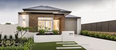 a brick house with grass and plants in the front yard