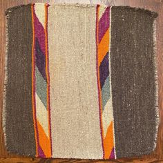 a brown and orange striped rug sitting on top of a wooden floor next to a wall