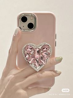 a woman's hand holding an iphone case with a heart shaped diamond on it