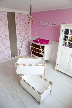 a room with pink walls and white furniture in the corner is filled with storage boxes