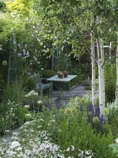 the garden is full of flowers, trees, and benches in it's natural setting