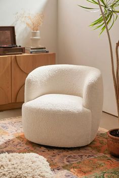 a white chair sitting on top of a rug next to a potted plant