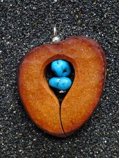 two blue beads are in the middle of a heart shaped wooden object on concrete ground