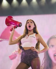 a woman holding a red hair dryer on top of her head while standing in front of a crowd