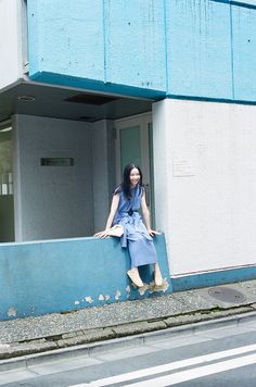 a woman leaning against the side of a building