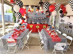 a party setup with checkered table cloths and black and white balloons on the ceiling