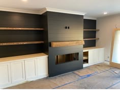 an empty room with some shelves on the wall and a fireplace in the middle that's being built