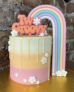 a cake with icing and flowers on top, next to a rainbow shaped cake