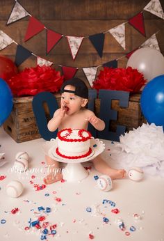 a baby sitting in front of a cake with red, white and blue decorations