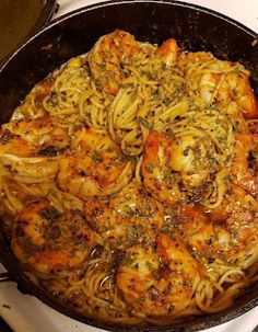 a pan filled with pasta and shrimp on top of a stove