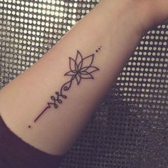 a small wrist tattoo with a flower on the middle of it and an arrow in the middle