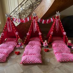 some pink and white striped beds with teddy bears on them in front of a stair case