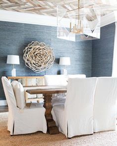 a dining room with blue walls and white chairs