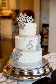 a three tiered wedding cake with snowflakes on top