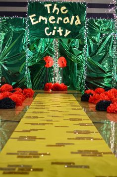 an image of a long yellow table with red flowers on it and the words the emerald city