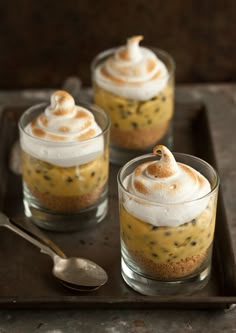 three desserts are sitting on a tray with spoons