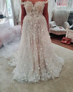 a woman standing in front of a mirror wearing a wedding dress with flowers on it