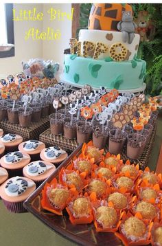 an assortment of cupcakes and desserts displayed on trays in front of a cake