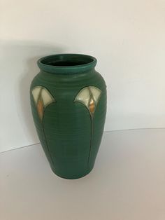 a green vase sitting on top of a white table