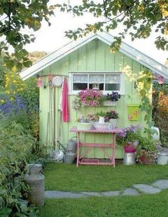 a garden shed with flowers and potted plants on the outside, in front of it