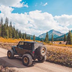 a jeep driving down a dirt road in the mountains