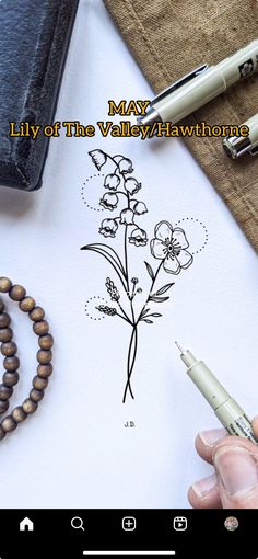 a person is drawing flowers on paper with a pen and some other items next to it