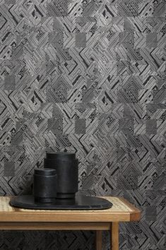 a wooden table with a black plate on top of it next to a wallpaper