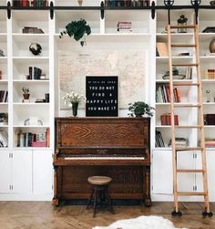 a living room with bookshelves and a piano in the corner, next to a ladder