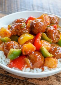 a white bowl filled with meat and veggies over rice on top of a wooden table