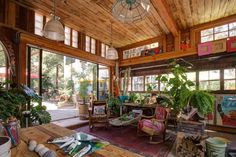 a living room filled with lots of furniture and plants on top of a wooden floor