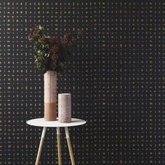 two vases with flowers sit on a small table against a wallpapered background