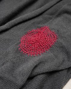 a close up of a knitted blanket with a red circle on it's center