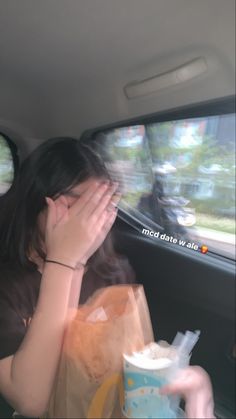 a woman sitting in the back seat of a car with her hand on her face