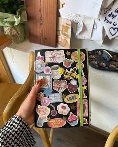 a person holding up a book with stickers on it