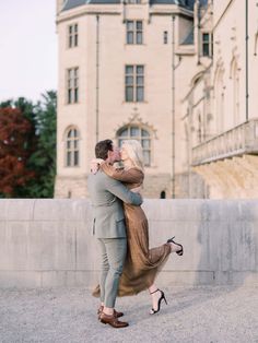 a man and woman hugging in front of a large building