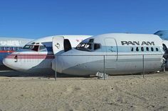 an airplane is parked behind a fence on the dirt ground with another plane in the background