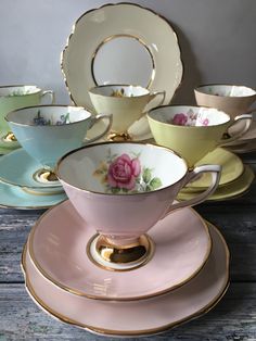 a set of tea cups and saucers with pink roses on them sitting on top of each other