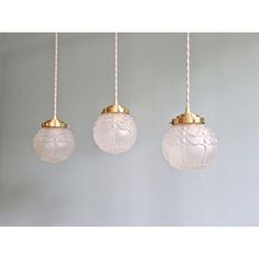 three white glass balls hanging from ropes in a room with light blue walls and flooring