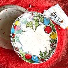 a white plate with christmas decorations on it next to a red table cloth and napkin