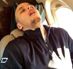 a man sleeping on an airplane seat with his eyes closed and head tilted to the side