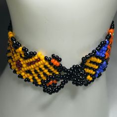 a multicolored beaded necklace is displayed on a mannequin