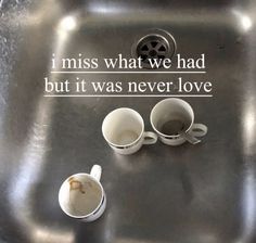 two coffee mugs sitting on top of a metal sink next to a quote that reads, i miss what we had but it was never love