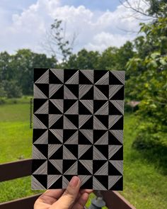 a hand holding up a piece of paper with black and white geometric designs on it