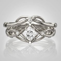 a white gold ring with a princess cut diamond in the center and two diamonds on each band